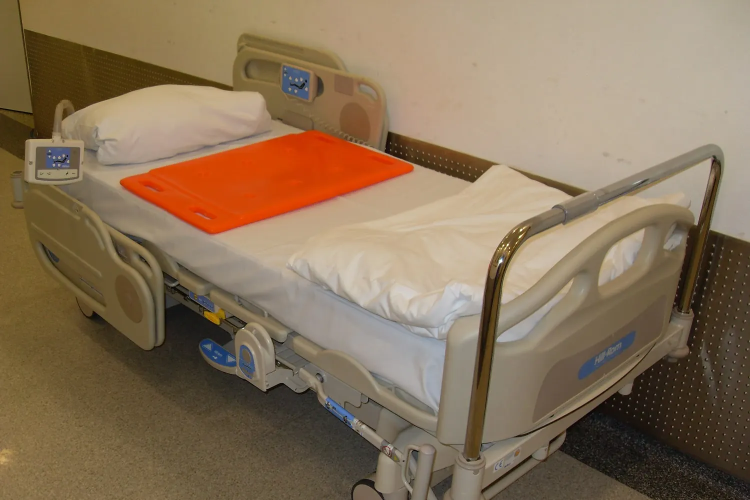 Cama hospitalar articulada com a cabeceira elevada e grades de proteção